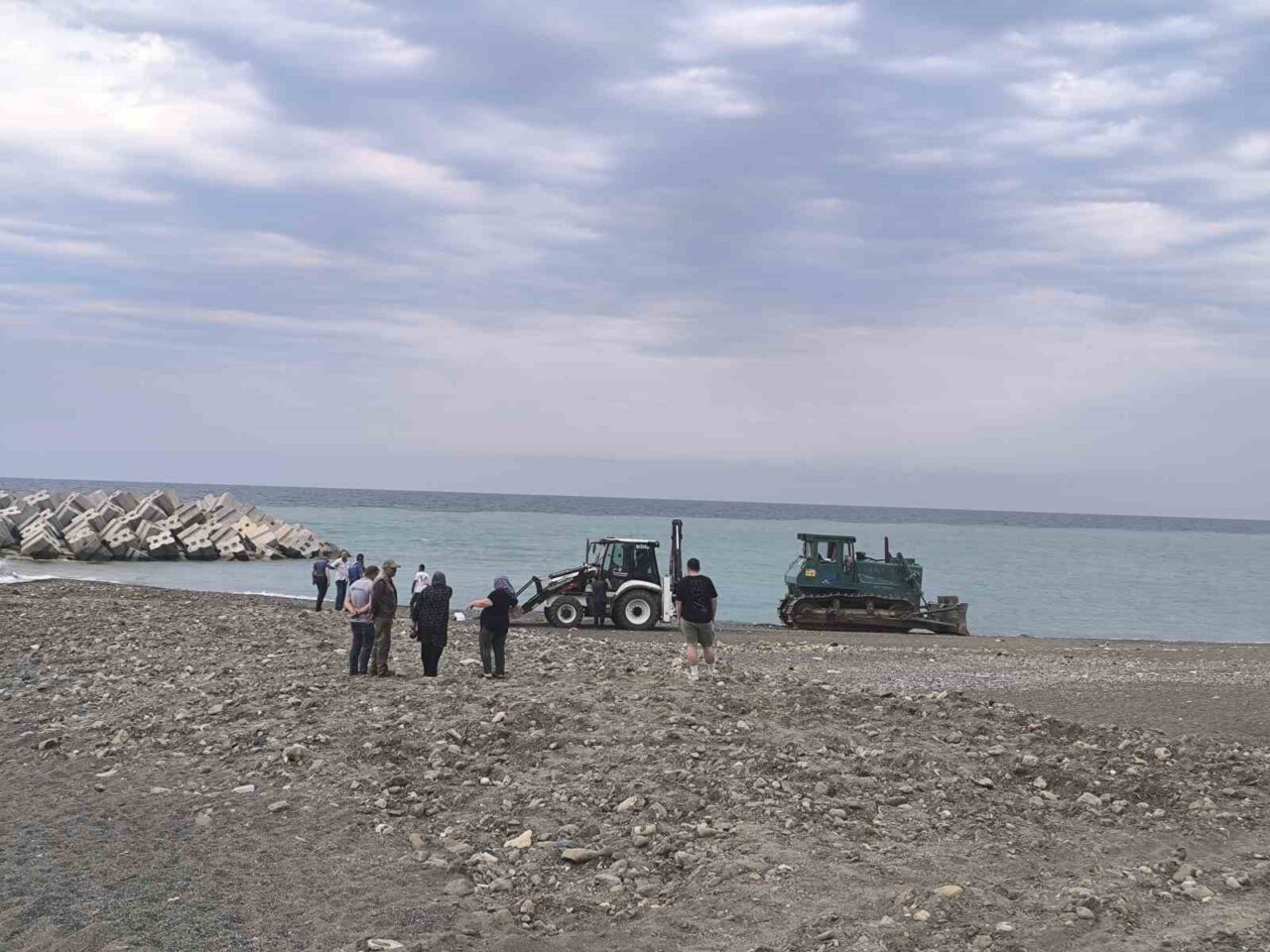 Kastamonu’nun Abana ilçesinde sahilde dinlenen kadın, temizlik yapan iş makinesinin