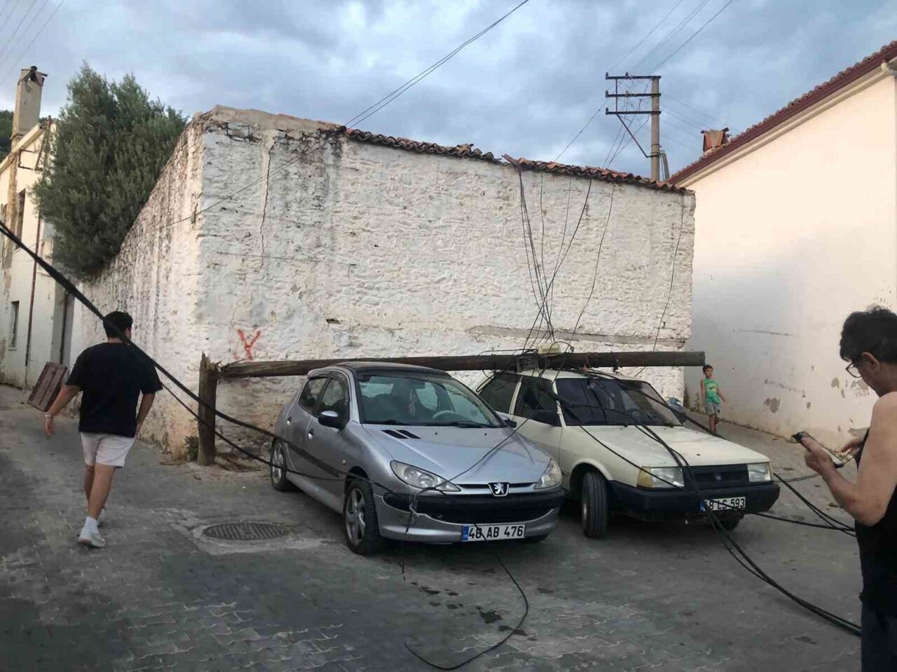 Menteşe Emirbeyazıt Mahallesi’nde bulunan ahşap direk, park halindeki iki otomobilin
