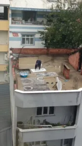 Bursa’da su kesintisi yapılırken, yağmur altında hortumla halı yıkayan bir