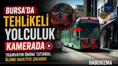 Bursa’da seyir halindeki tramvayın arkasına tutunarak yolculuk yapan iki çocuk,