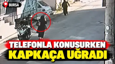 Bursa’da yolda yürürken telefonla konuşan kadının elindeki cep telefonunu motosikletle